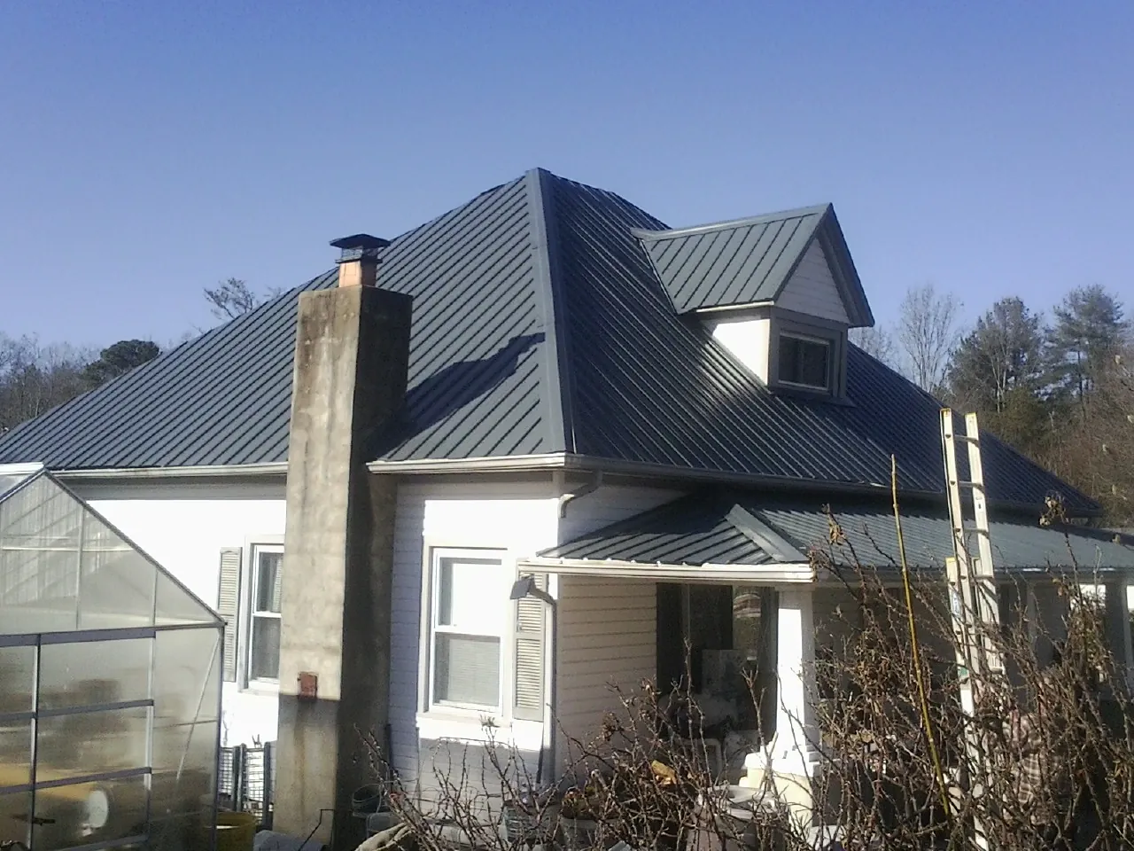 Dark blue standing seam metal roof on a white farmhouse with dormer — Slate & Tile Roof Repair by Roofing Brothers in Summit Hill