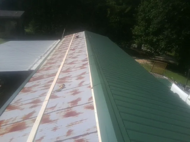 Old rusted panels beside newly installed green metal roofing — Wind Damage Roof Repair by Roofing Brothers in Summit Hill
