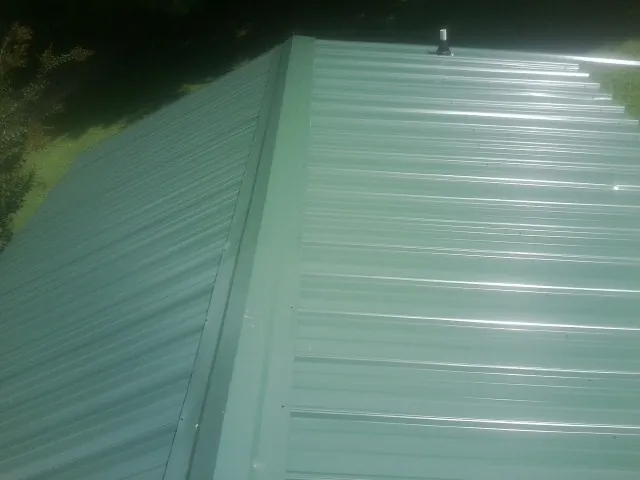 New green metal panels meeting at the ridge of a roof — Flat Roof Repair work by our crew in Summit Hill