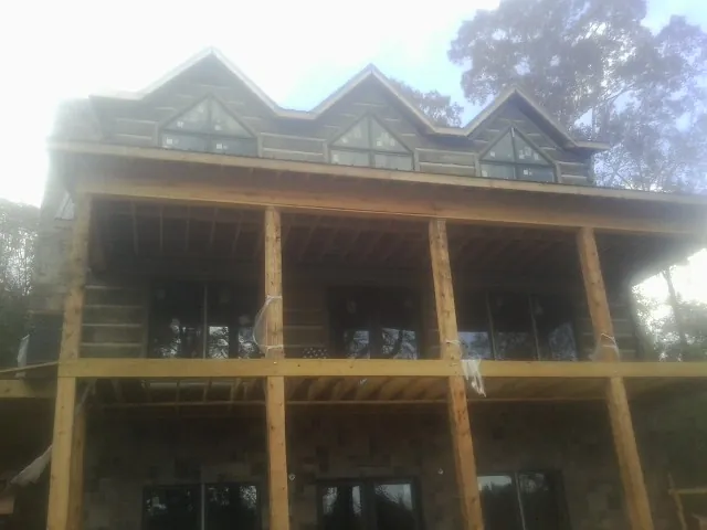 Dormers and porch framing on a large log home under construction — Roof Coating work by our crew in Summit Hill