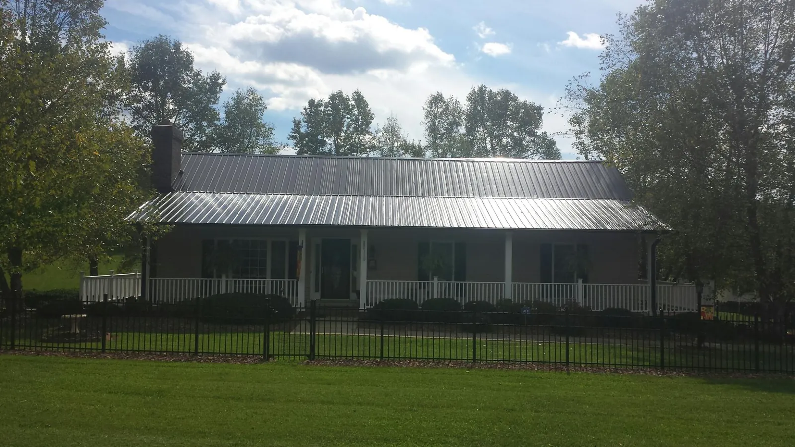 Gray metal roof on a brick ranch with a full width front porch — Gutter Guard Installation work by our crew in Summit Hill