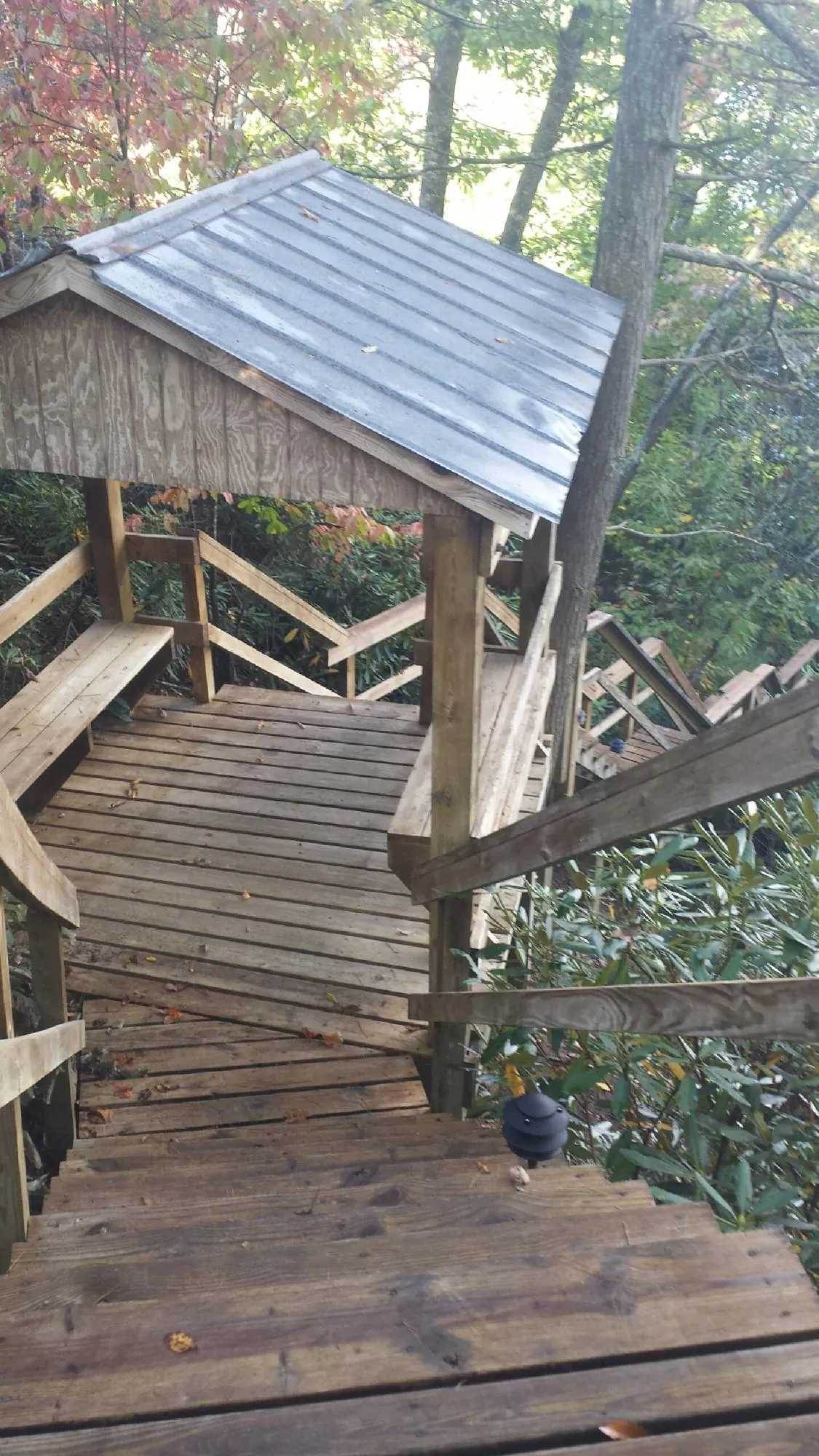 Metal roofed shelter over wooden steps on a wooded walkway — Skylight Repair & Installation work by our crew in Summit Hill
