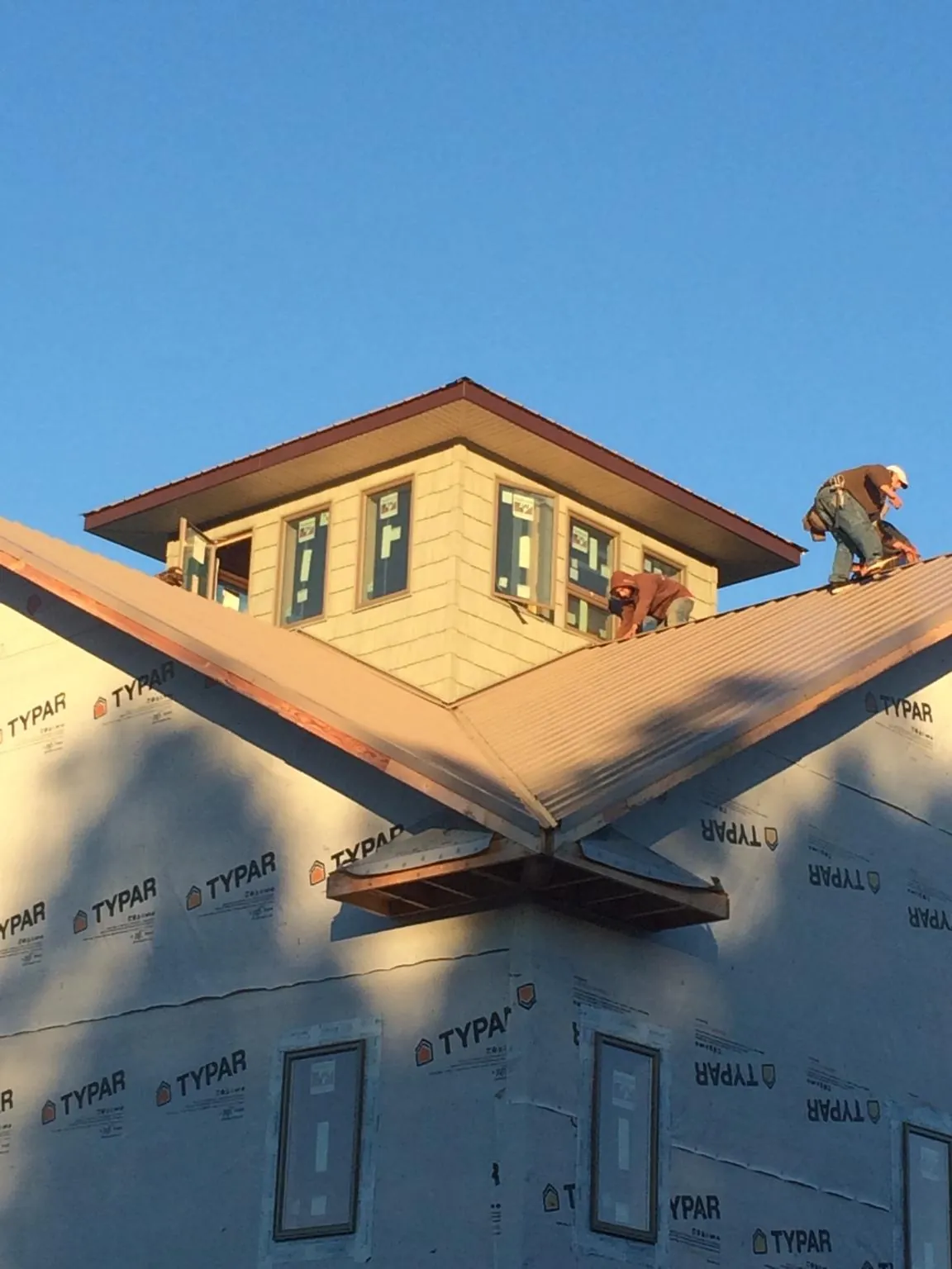 Roofers working around a rooftop cupola on a new metal roof at sunset — Roof Waterproofing in Summit Hill by Roofing Brothers
